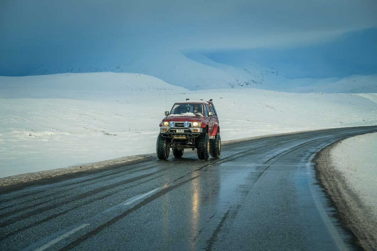 masina inalta rosie de teren pe drum extravilan la munte cu zapada